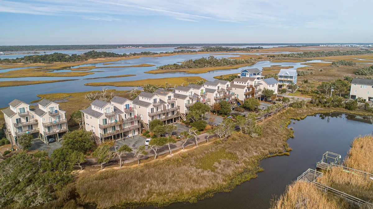 A serene exterior shot capturing marshland, waterfront properties, and a distant horizon. The openness of the landscape suggests opportunities for nature walks, birdwatching, and peaceful strolls—echoing the dog-friendly, outdoorsy appeal described in the narrative.