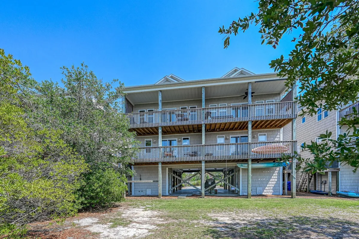 A multi-level exterior balcony with exposed wooden beams and surrounding greenery. Ample space for family gatherings or relaxing outdoors, with views overlooking marshlands and the Intracoastal Waterway.